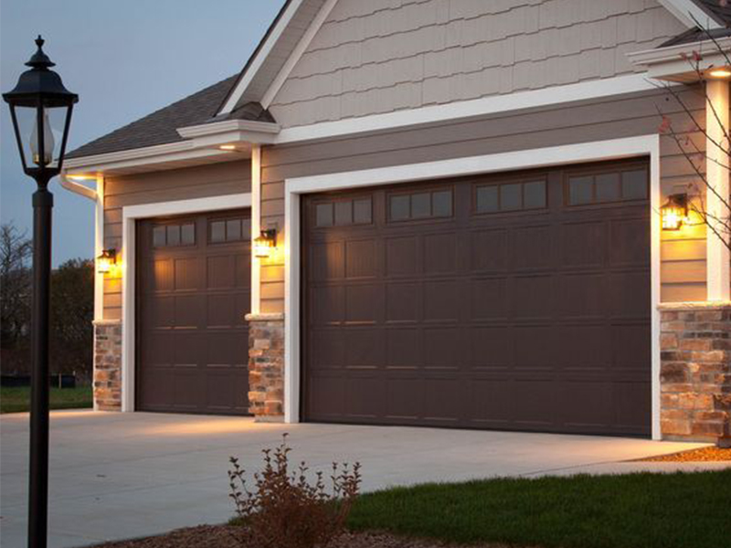 A couple of brown garage doors in front of a house.